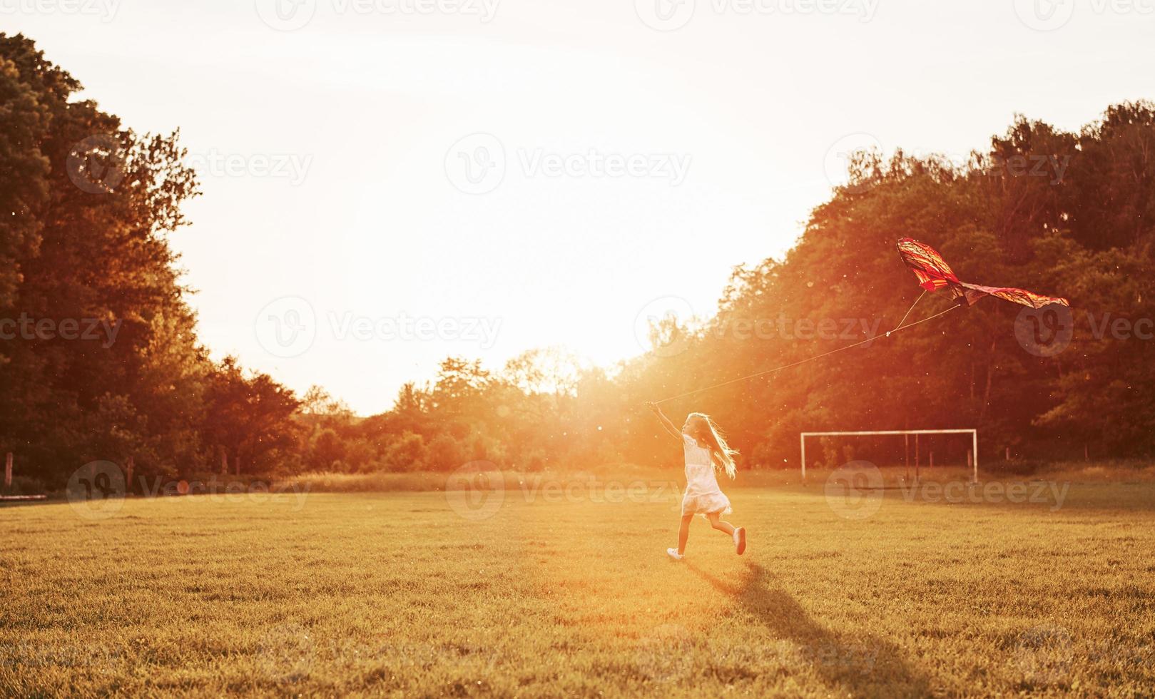 concepção do tempo de lazer. garota feliz em roupas brancas divirta-se com pipa no campo. natureza bela foto