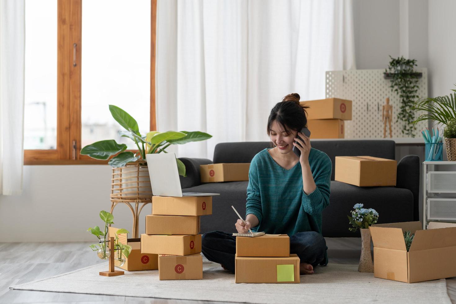 empreendedores pequenas empresas sme mulher independente trabalham em casa usam smartphones e laptops para verificação comercial, marketing on-line, caixas de embalagem, vendedores de sme, conceito, equipe de comércio eletrônico foto