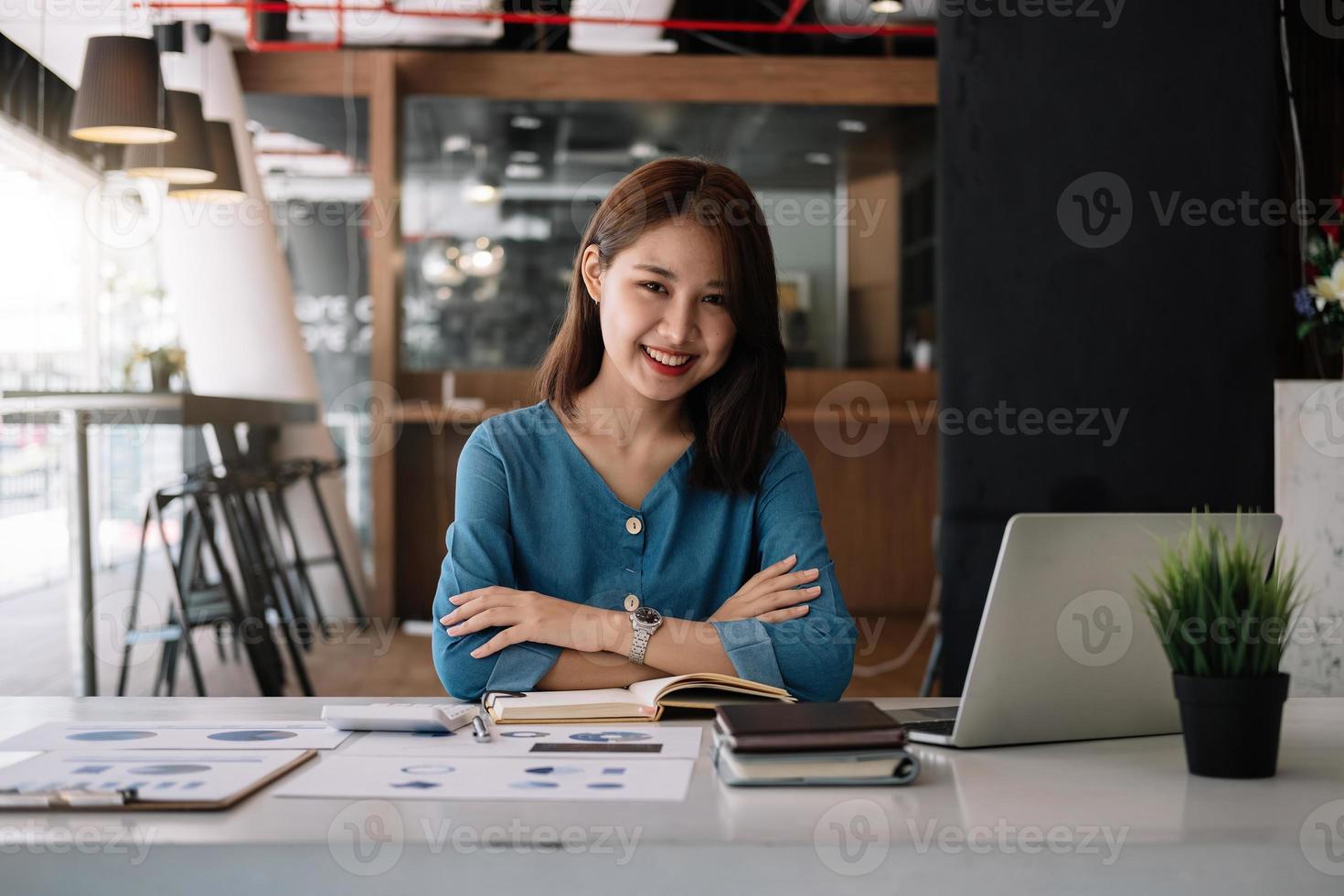 retrato encantador mulher asiática sorrindo para o escritório. mulher trabalhando para cálculo financeiro com computador portátil e papelada foto