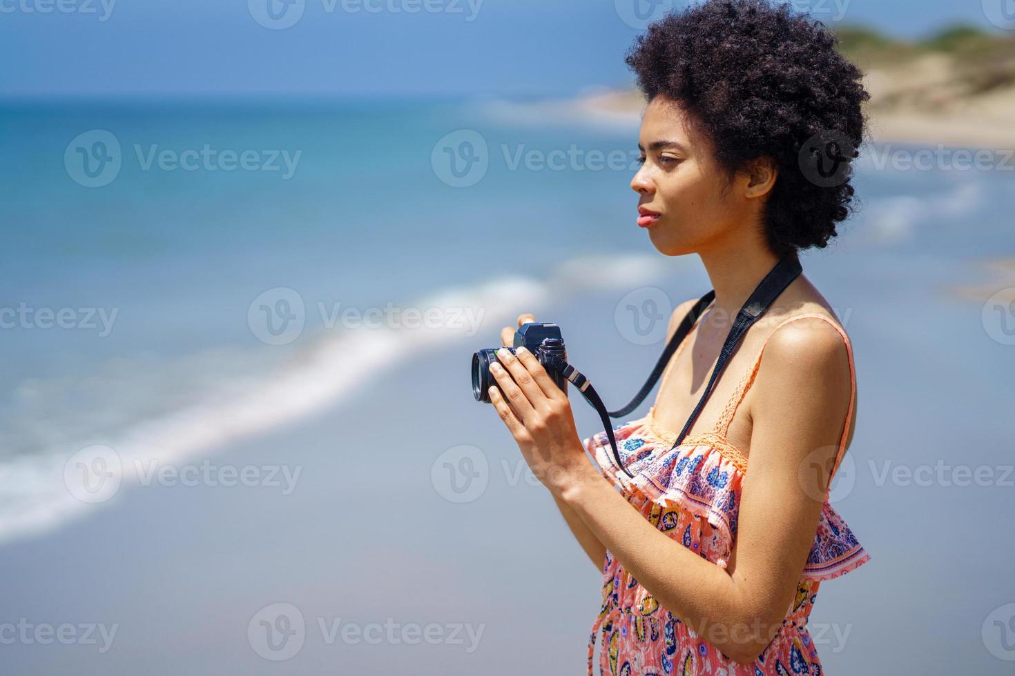 mulher negra com câmera na praia foto