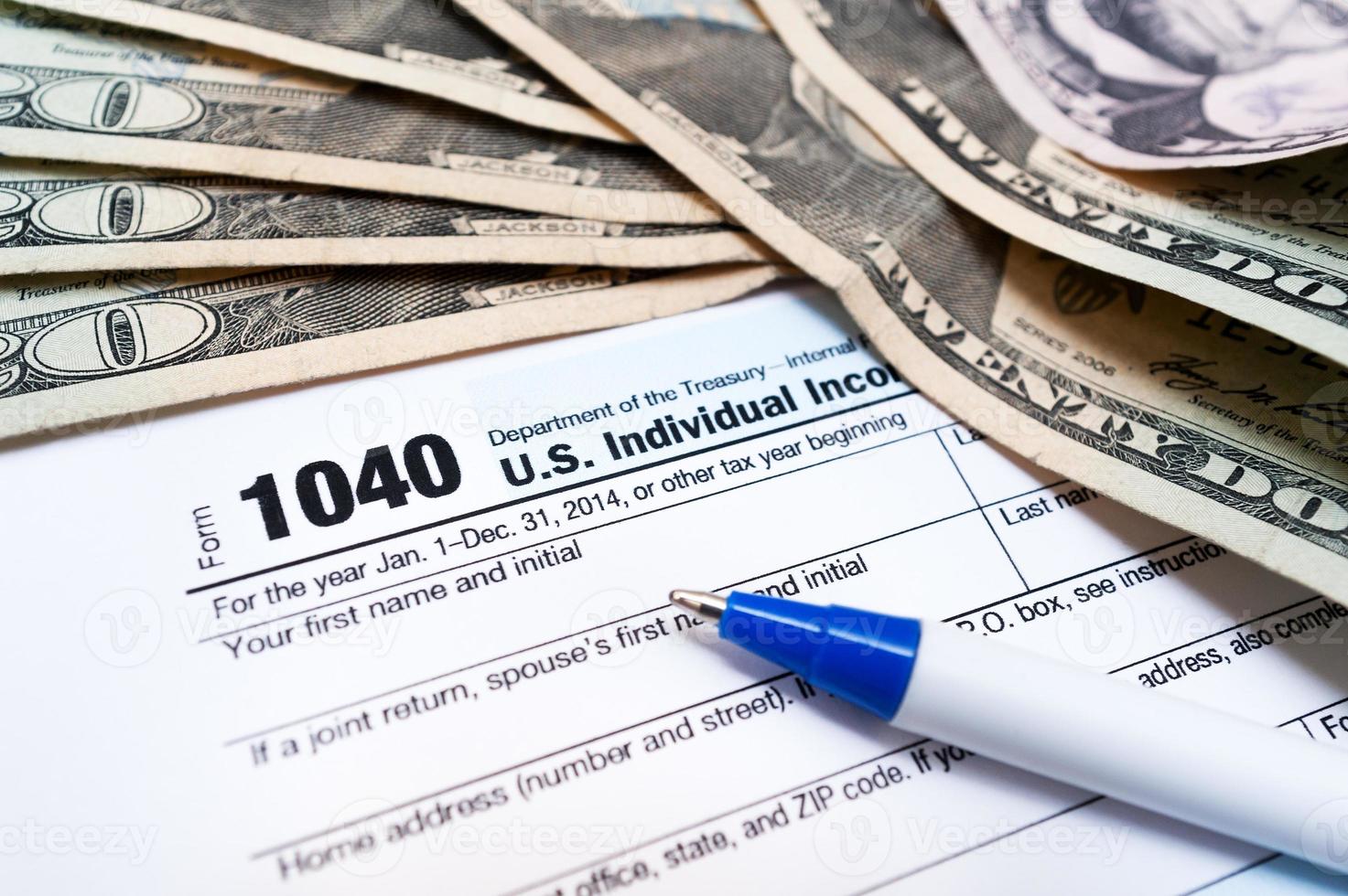 Formulário de declaração de imposto individual 1040 close-up com caneta e dólares foto