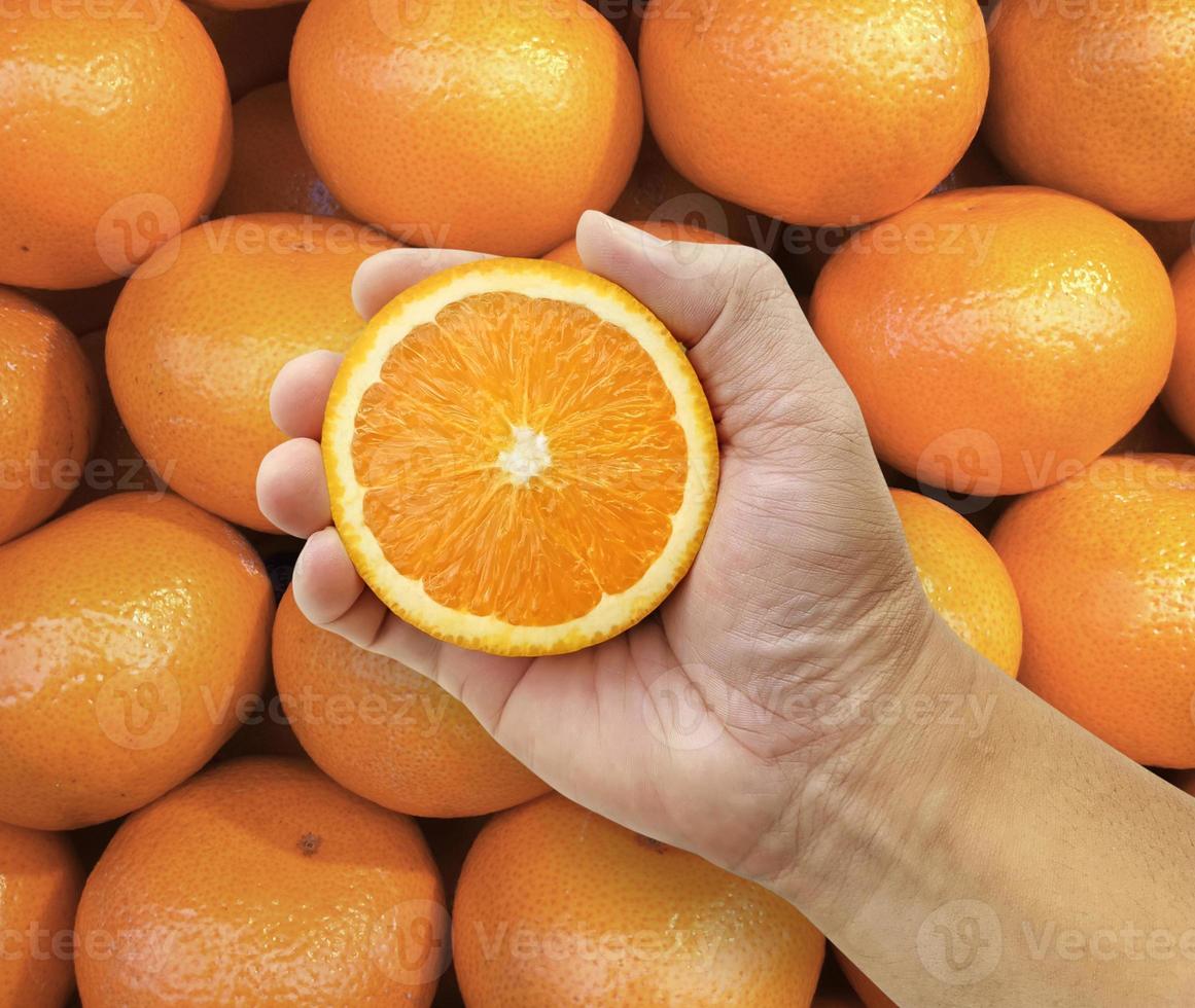 mão segurando a fruta laranja no fundo da fruta laranja foto