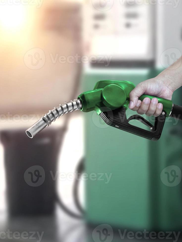 homem segurando o bico de combustível no posto de gasolina foto