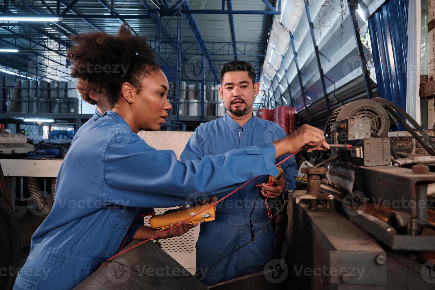 equipes de engenheiros profissionais multirraciais da indústria em uniformes de segurança trabalham inspecionando a corrente de tensão das máquinas, verificando e mantendo na fábrica de fabricação, ocupações de serviço do sistema elétrico. foto