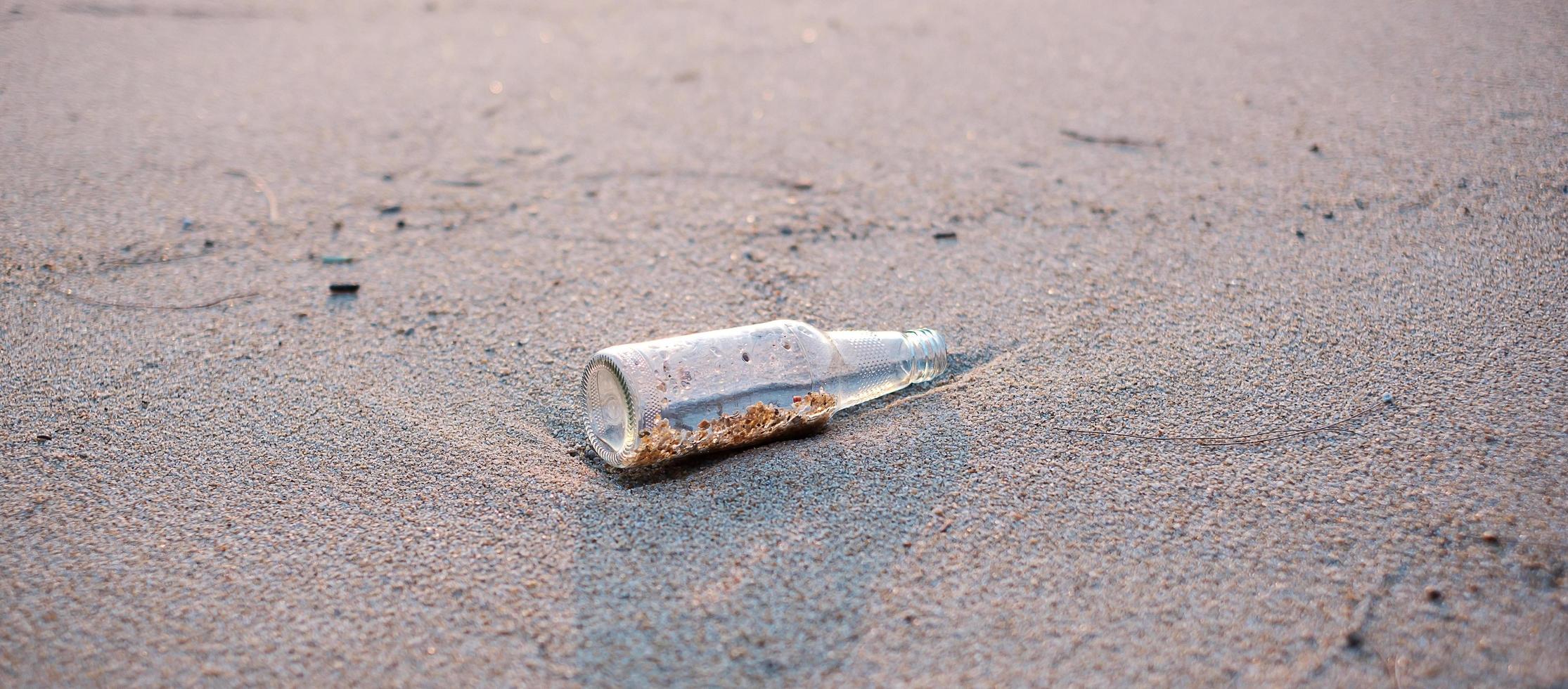 lixo de garrafa de vidro na praia. ecologia, meio ambiente, poluição e conceito de problema ecológico foto