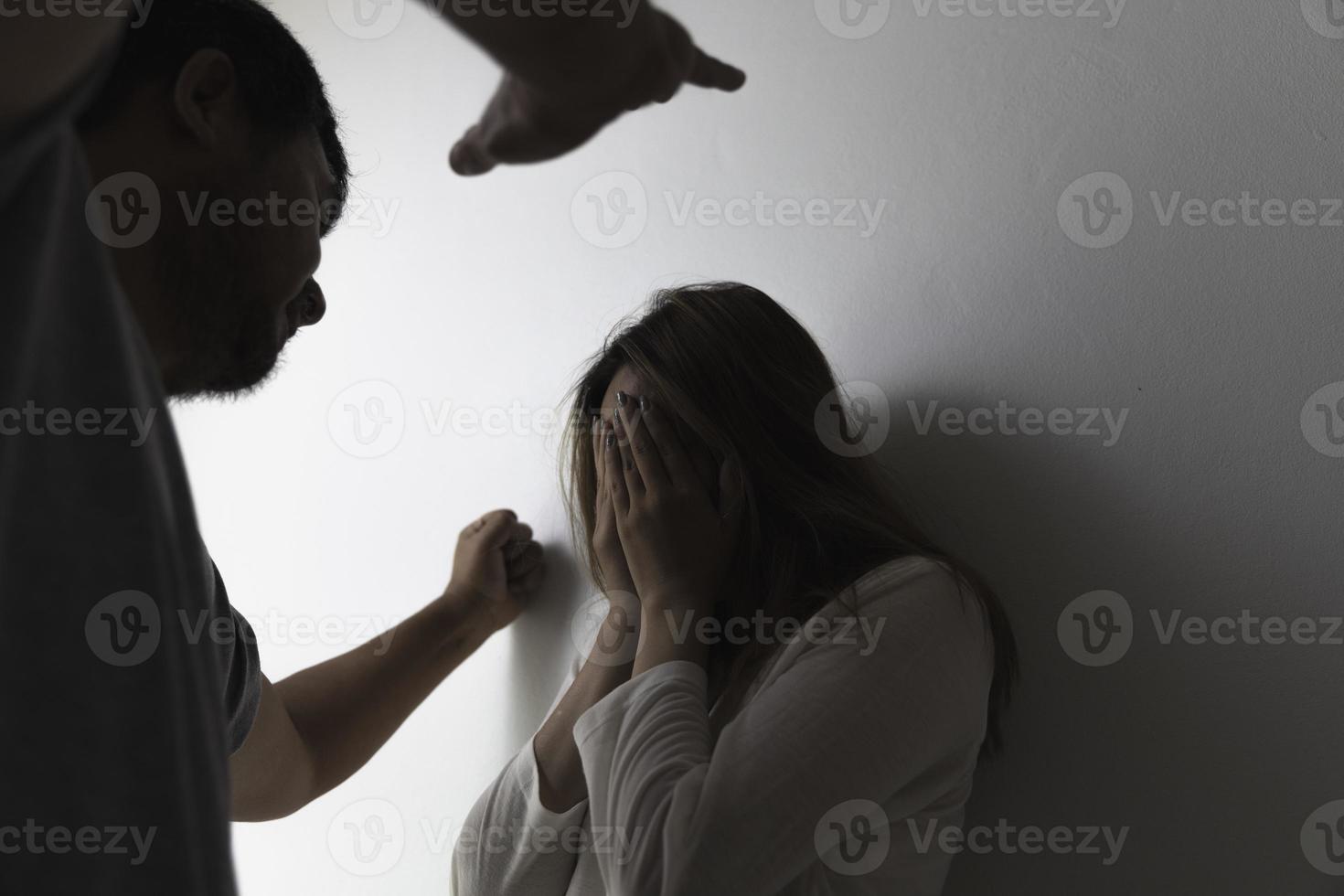 close-up do punho de um homem com raiva e uma mulher assustada no fundo, ela cobre o rosto com as mãos. foto
