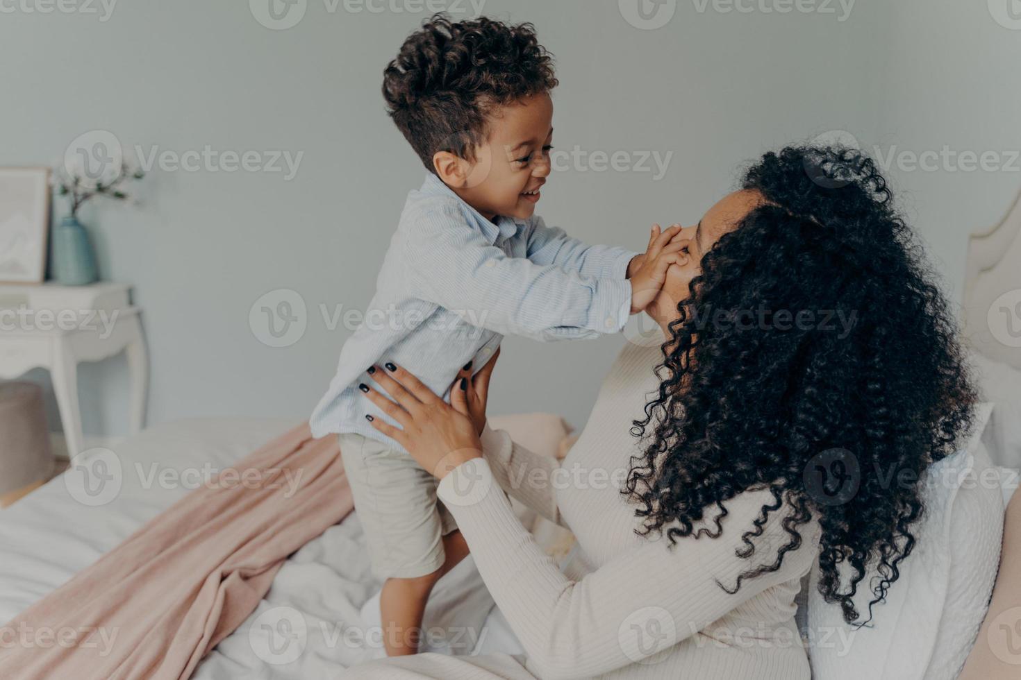 senhora afro-americana grávida brincando com seu filho em casa foto