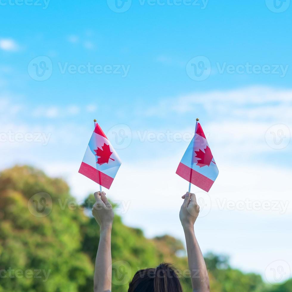 mão segurando a bandeira do Canadá no fundo do céu azul. dia do canadá e conceitos de celebração feliz foto
