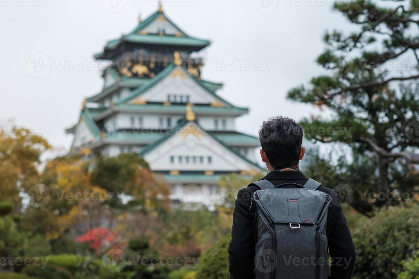 turista de homem solo viajando no castelo de osaka na temporada de outono, visita de viajante asiático na cidade de osaka, japão. férias, destino e conceito de viagem foto