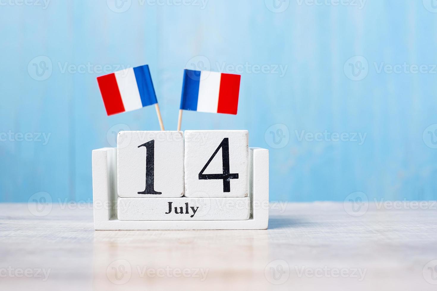 calendário de madeira de 14 de julho com bandeiras em miniatura da frança. dia nacional francês, dia da bastilha e conceitos de celebração feliz foto