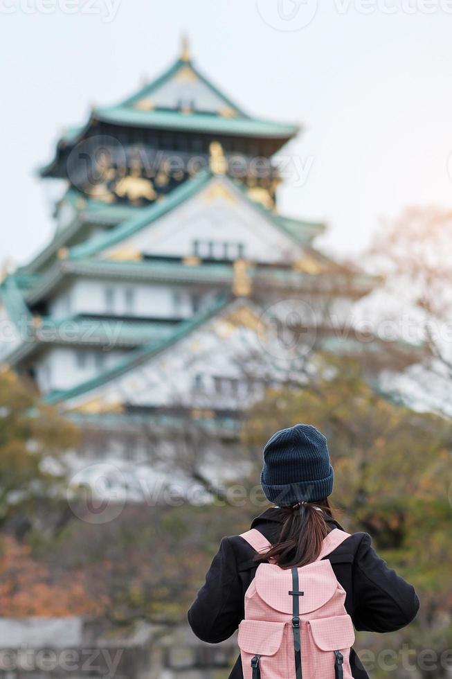 turista de mulher solo viajando no castelo de osaka na temporada de outono, visita de viajante asiático na cidade de osaka, japão. férias, destino e conceito de viagem foto