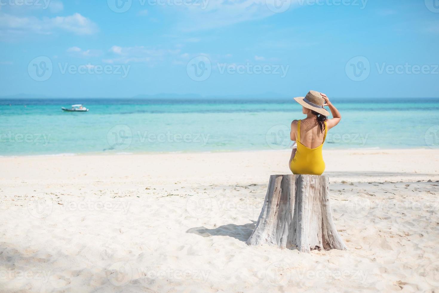 turista de mulher de maiô amarelo e chapéu, viajante solo olhando bela vista para o mar na ilha de bambu na ilha de phi phi don, krabi, tailândia. destino, viagens de verão, férias e conceito de férias foto