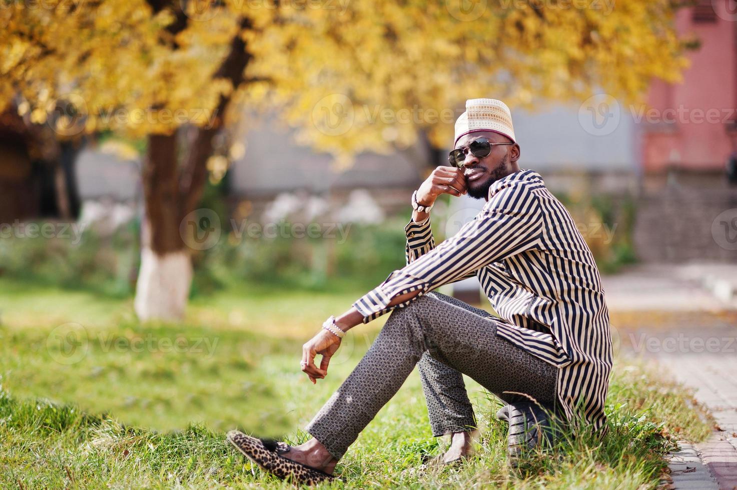 retrato de homem afro-americano elegante preto no chapéu e óculos de sol contra o fundo de outono ensolarado outono. pessoas ricas da áfrica em trajes tradicionais. foto