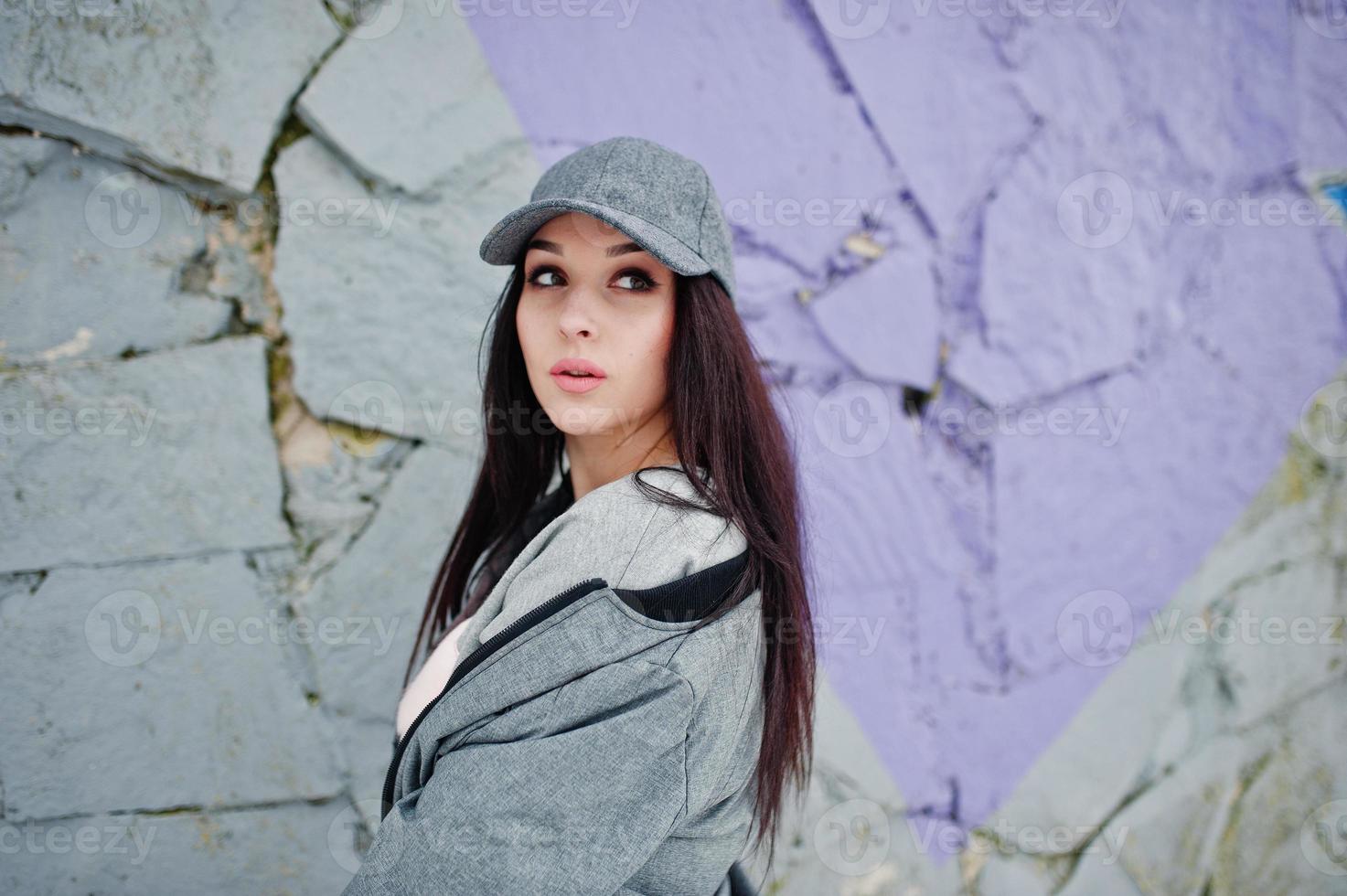 menina morena elegante boné cinza, estilo de rua casual em dia de inverno contra parede colorida. foto