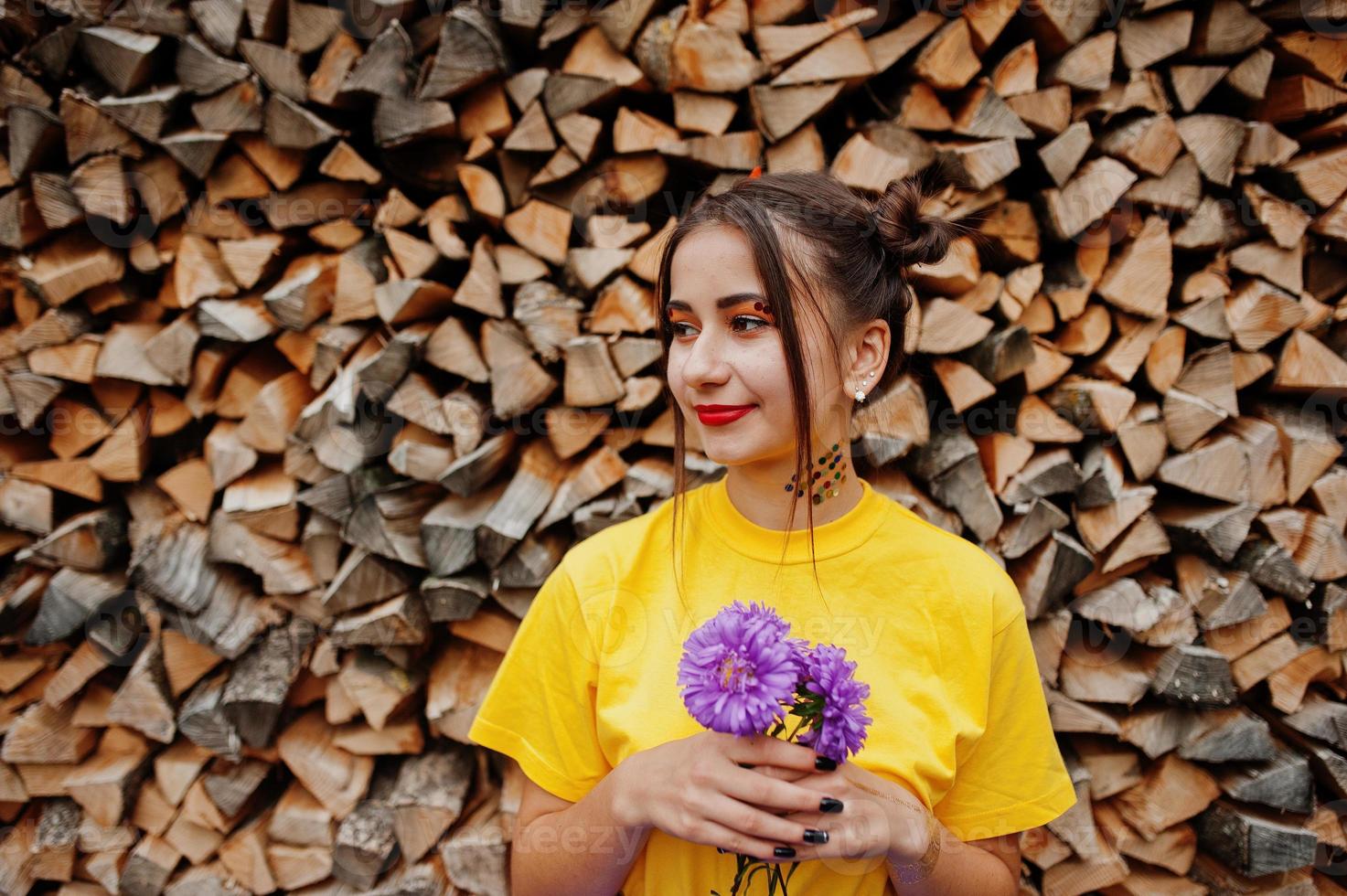 garota de camisa amarela com flores de áster violeta nas mãos. foto