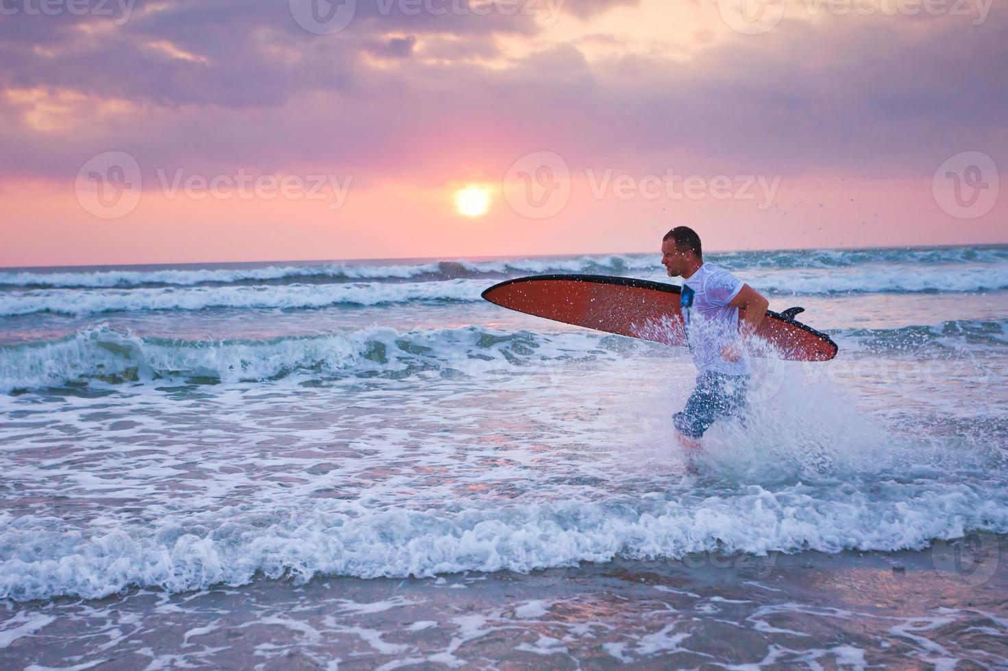 surfista correndo na costa na Indonésia foto