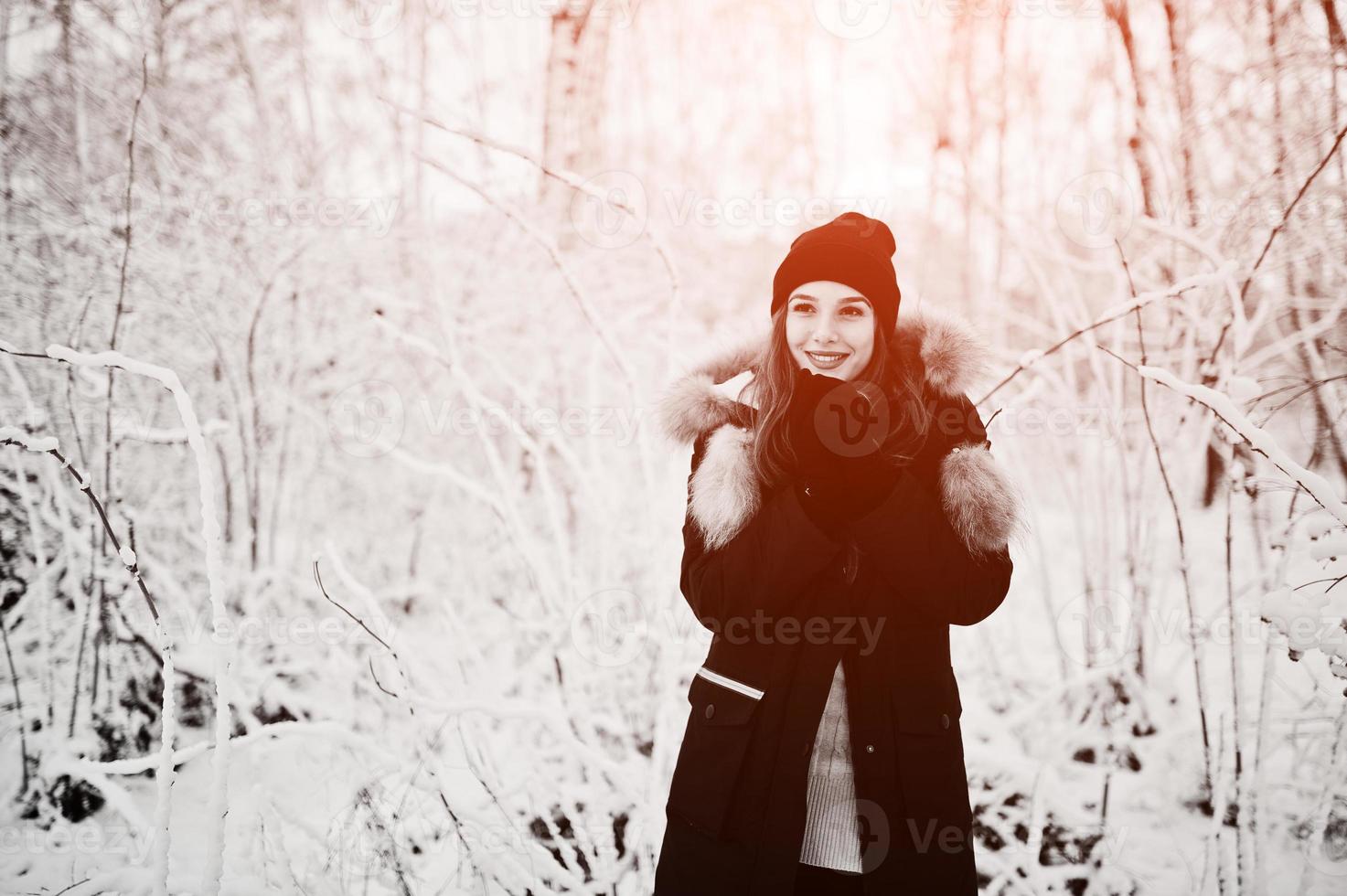 linda menina morena em roupas quentes de inverno. modelo de jaqueta de inverno e chapéu preto. foto