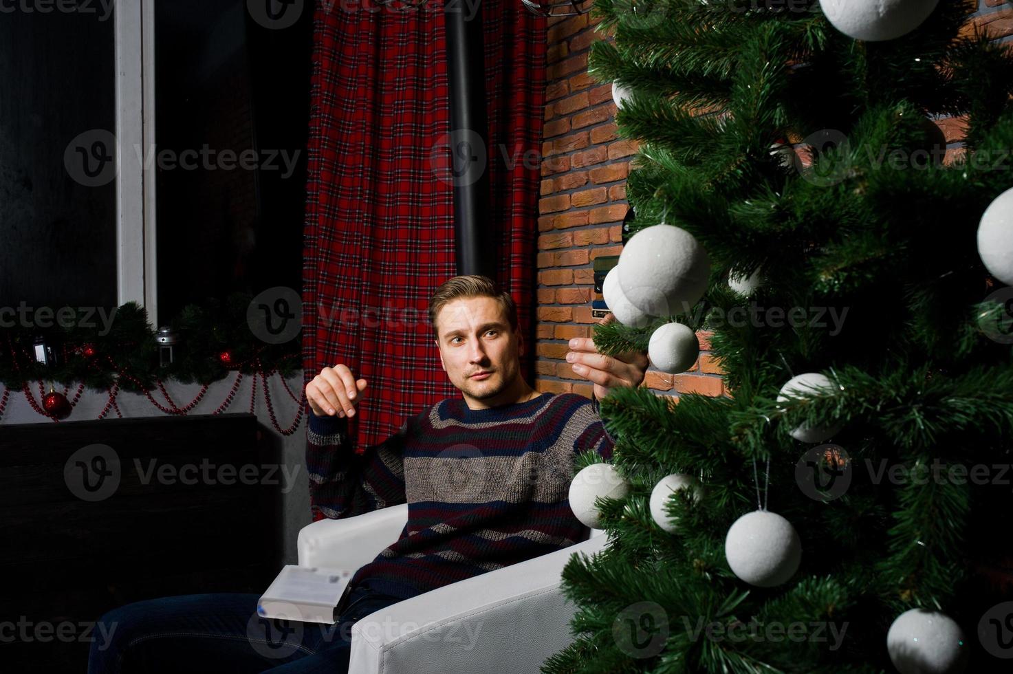 retrato de estúdio do homem contra a árvore de natal com enfeites. foto