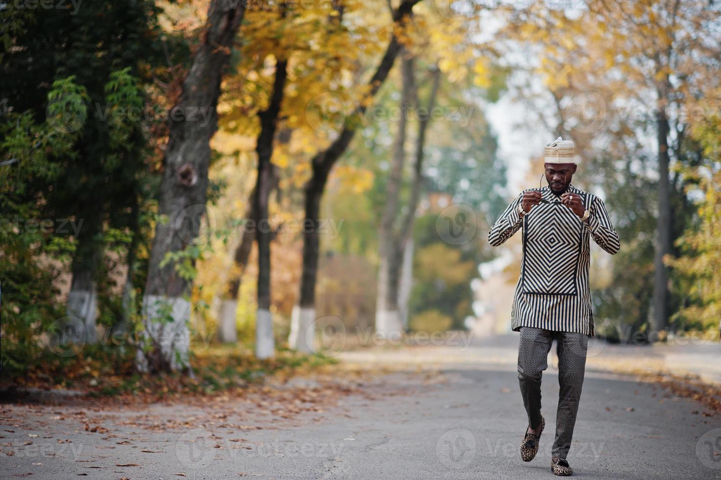 retrato de homem afro-americano elegante preto no chapéu e óculos de sol contra o fundo de outono ensolarado outono. pessoas ricas da áfrica em trajes tradicionais. foto
