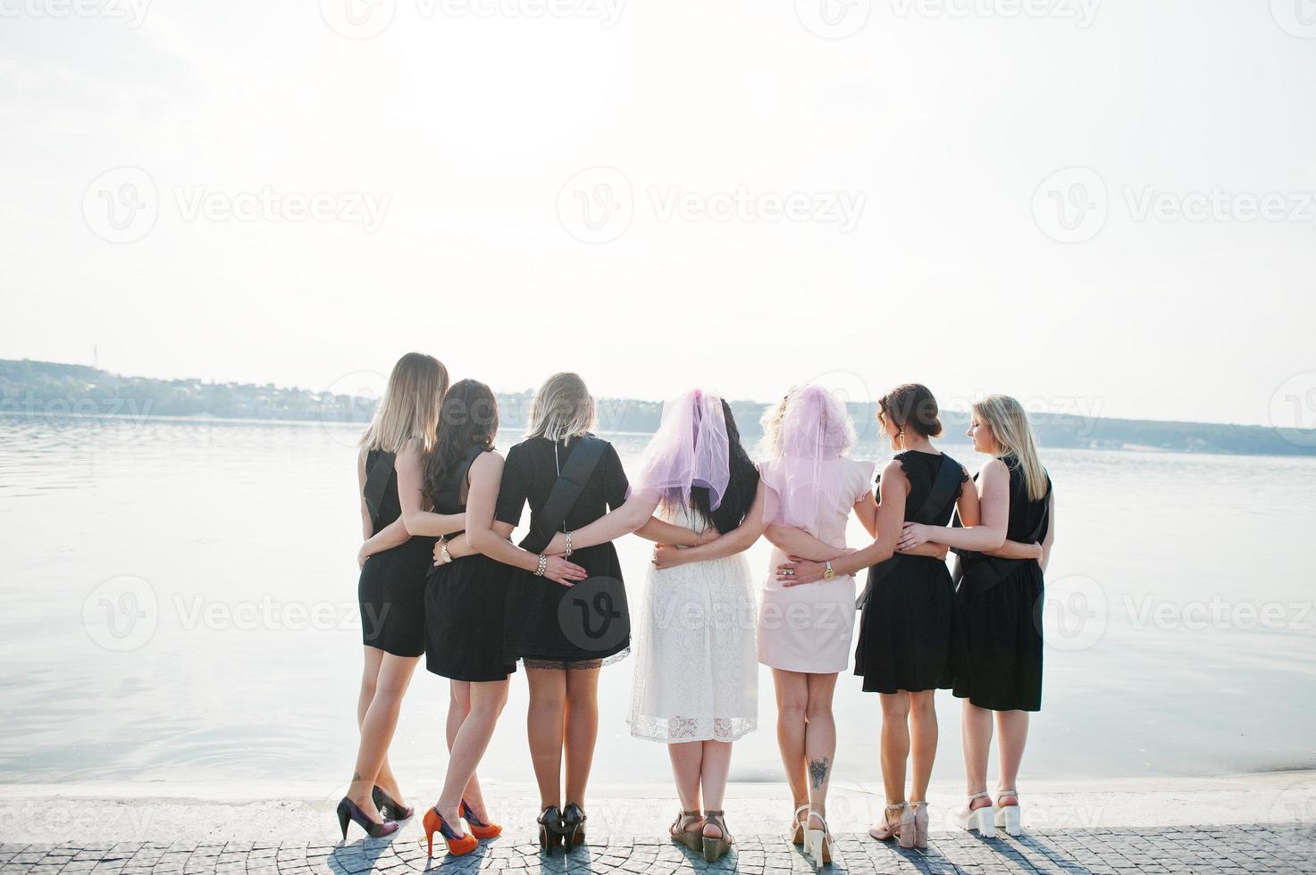 parte de trás do grupo de 7 meninas vestindo preto e 2 noivas na festa de despedida. foto