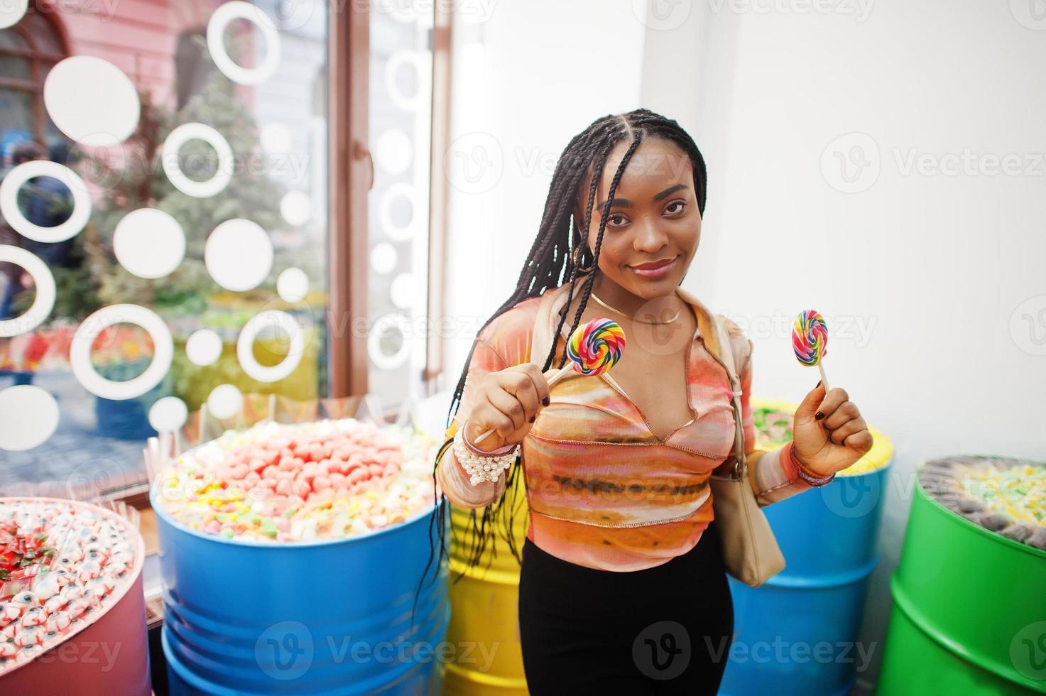 senhora milenar afro-americana na loja de doces com pirulitos. foto