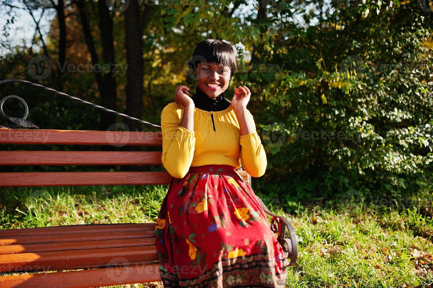 garota afro-americana no vestido amarelo e vermelho no outono outono park. foto