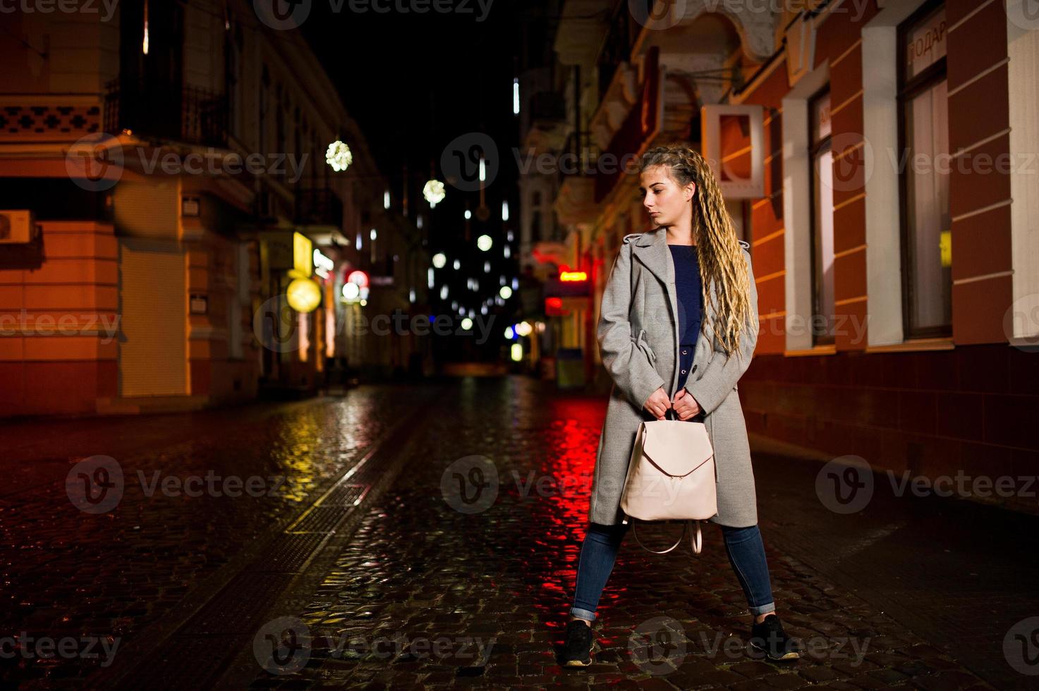 menina com dreadlocks andando na rua à noite da cidade. foto