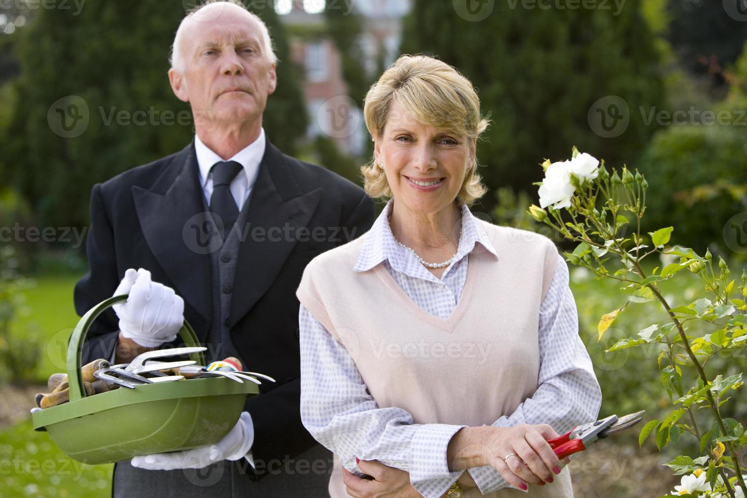mulher com tesouras de podar mordomo com cesta de ferramentas de jardinagem foto