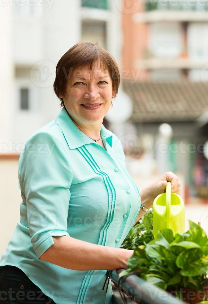 retrato de mulher idosa regando plantas domésticas foto