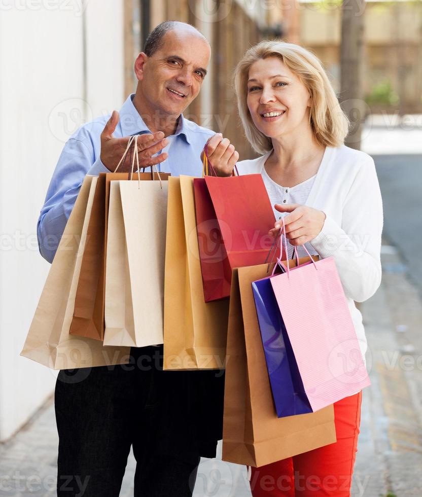 casal de idosos com sacos de compras nas mãos e sorrindo foto