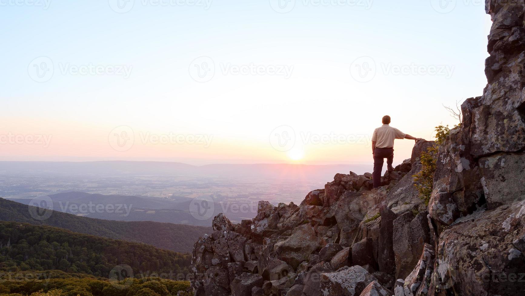 homem sênior assiste o nascer do sol sobre o cume azul foto