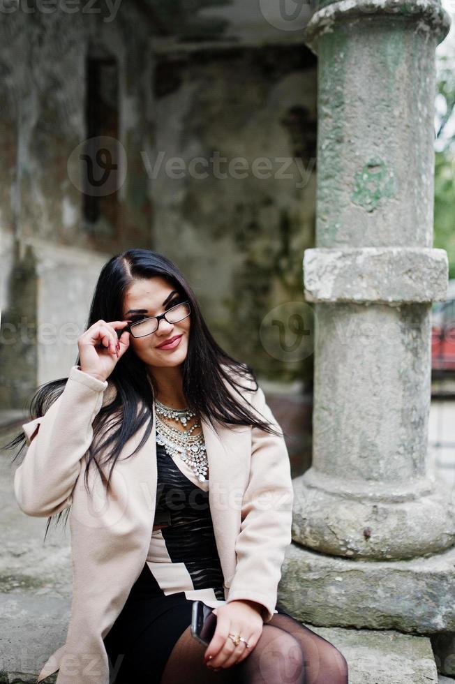 mulher sexy de cabelo preto de óculos e casaco posou na rua da cidade velha. foto