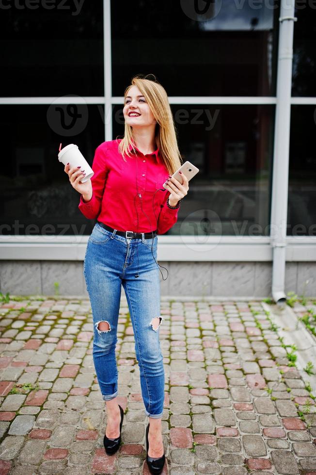 retrato de uma jovem atraente posando com café e smartphone fora do shopping. foto