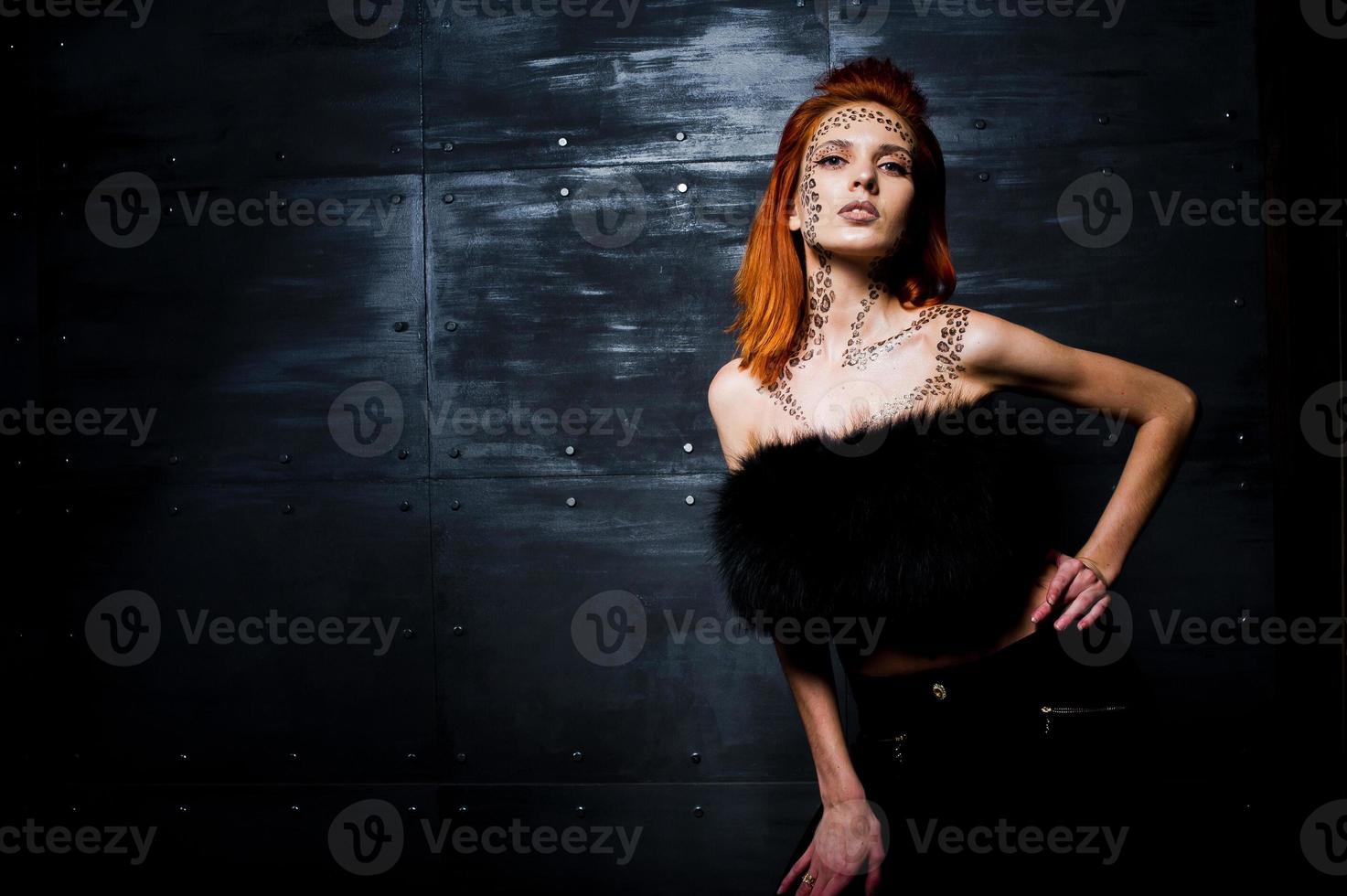 menina ruiva modelo de moda com maquiagem originalmente como predador leopardo contra parede de aço. retrato de estúdio. foto