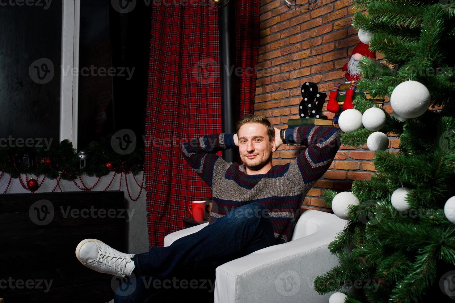 retrato de estúdio do homem contra a árvore de natal com enfeites. foto