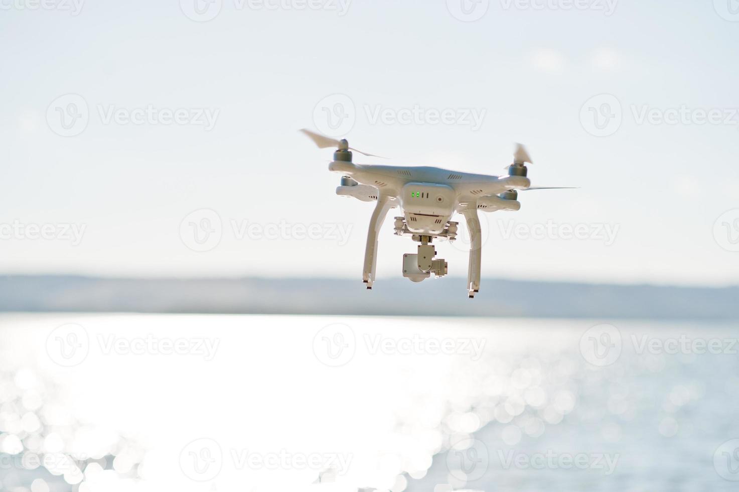 foto de close-up de um drone voando sobre o lago e tirando fotos dele.