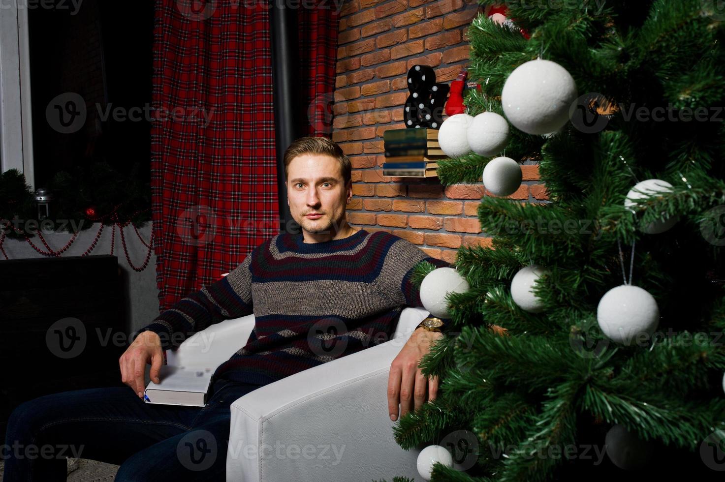 retrato de estúdio do homem contra a árvore de natal com enfeites. foto