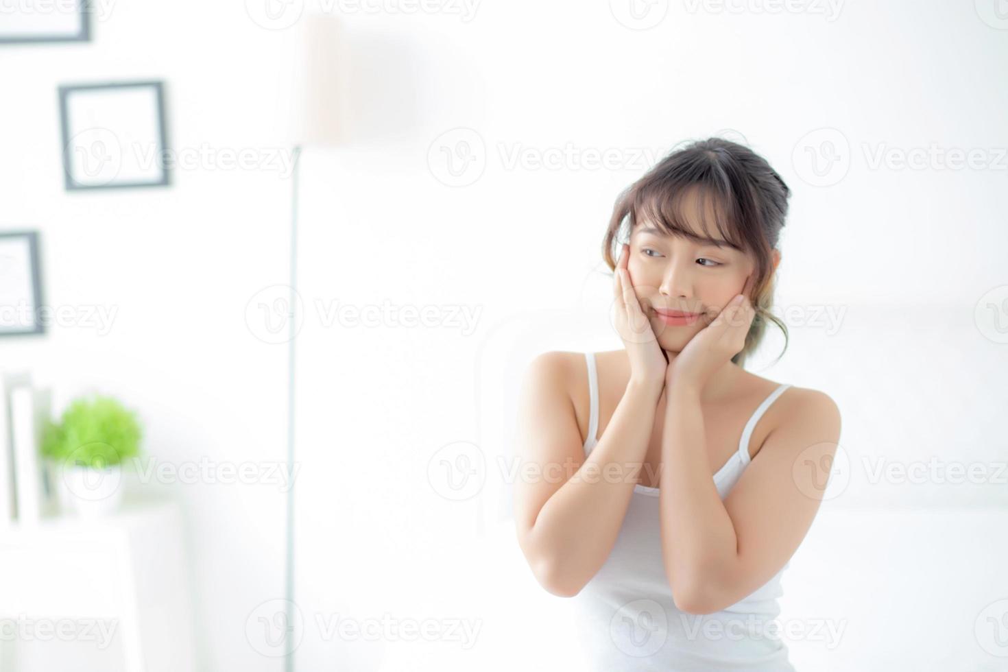 retrato de uma bela jovem asiática sorri enquanto acorda saudável e bem-estar com o nascer do sol de manhã no quarto, cuidados com a pele da menina da ásia com feliz com fresco, estilo de vida e conceito de relaxamento. foto