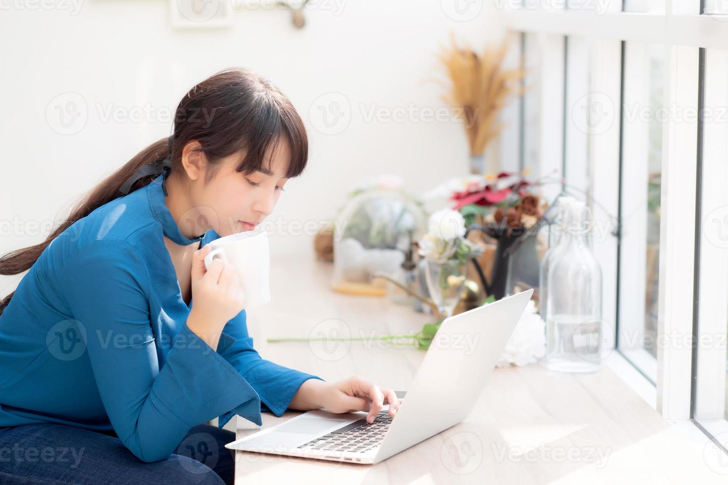 bela jovem mulher asiática freelance sorrindo trabalhando e no computador portátil na mesa de café com profissional, garota asiática usando notebook e bebida café, negócios e conceito de estilo de vida. foto