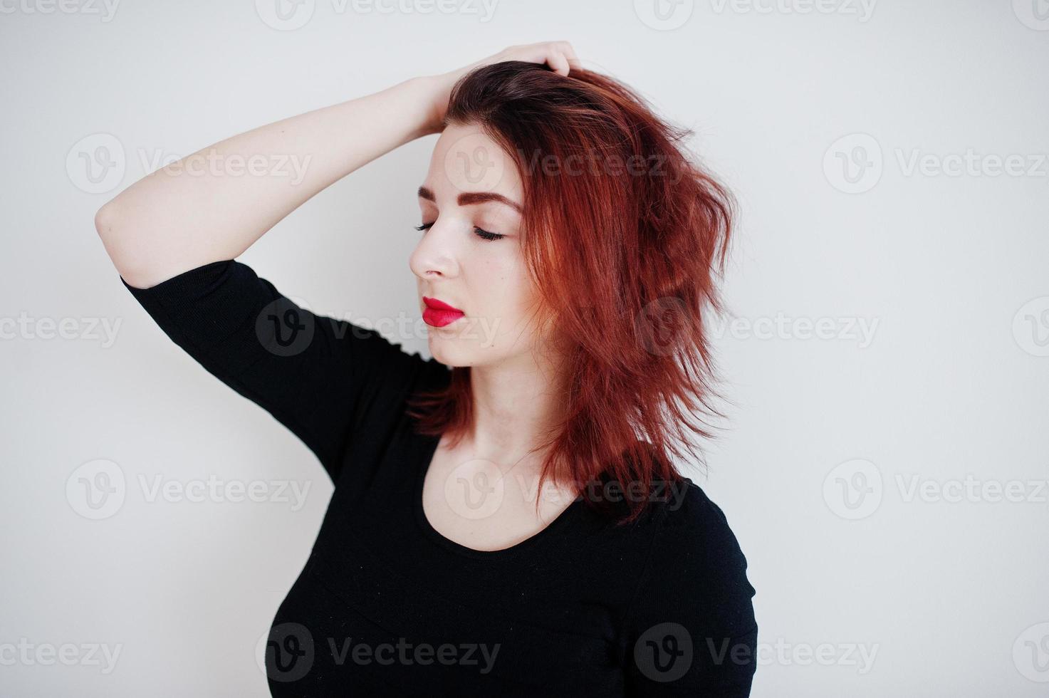 garota ruiva na túnica de vestido preto contra a parede branca no quarto vazio. foto