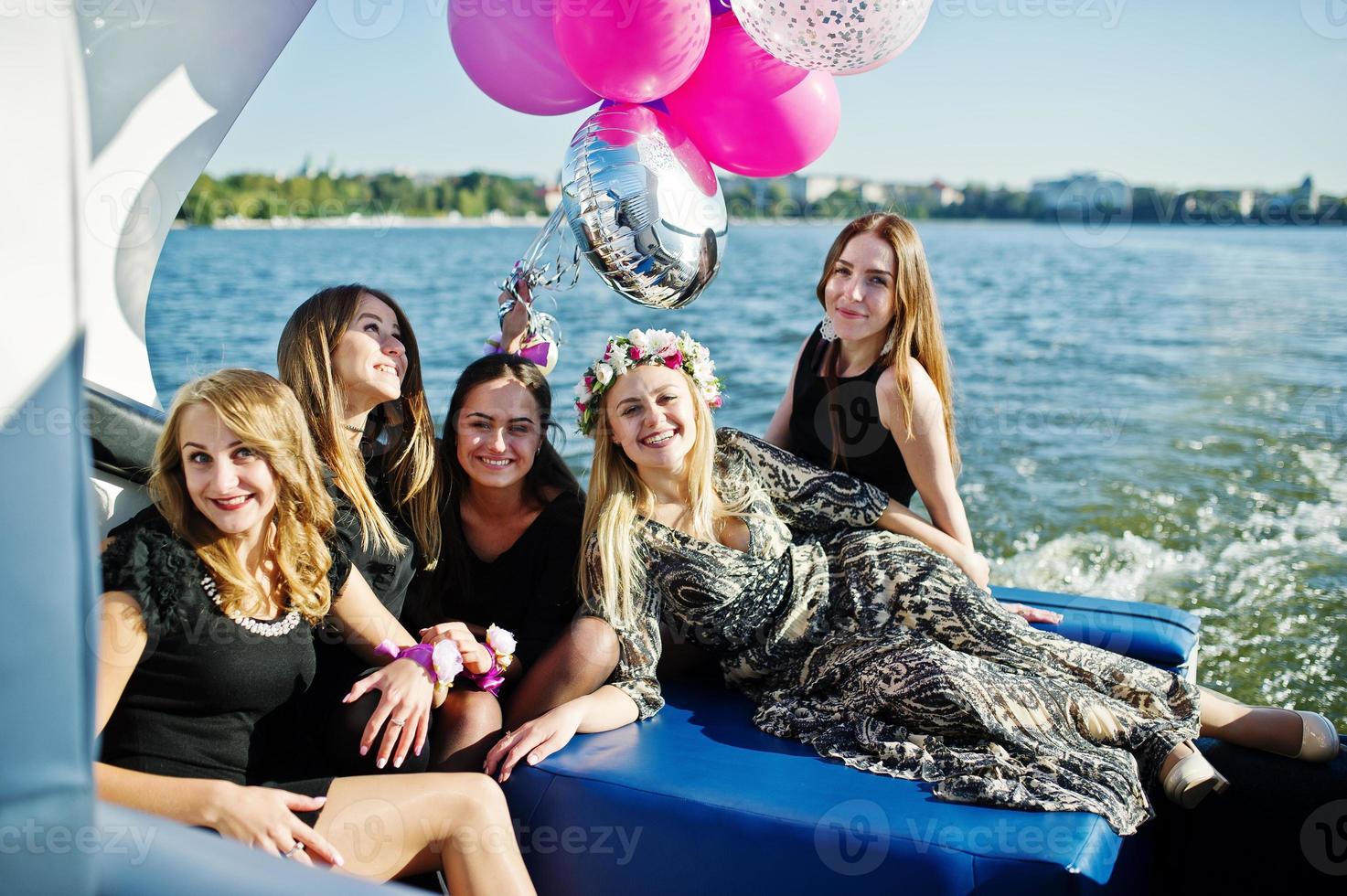 cinco garotas usam preto se divertindo no iate contra o lago na festa de despedida. foto