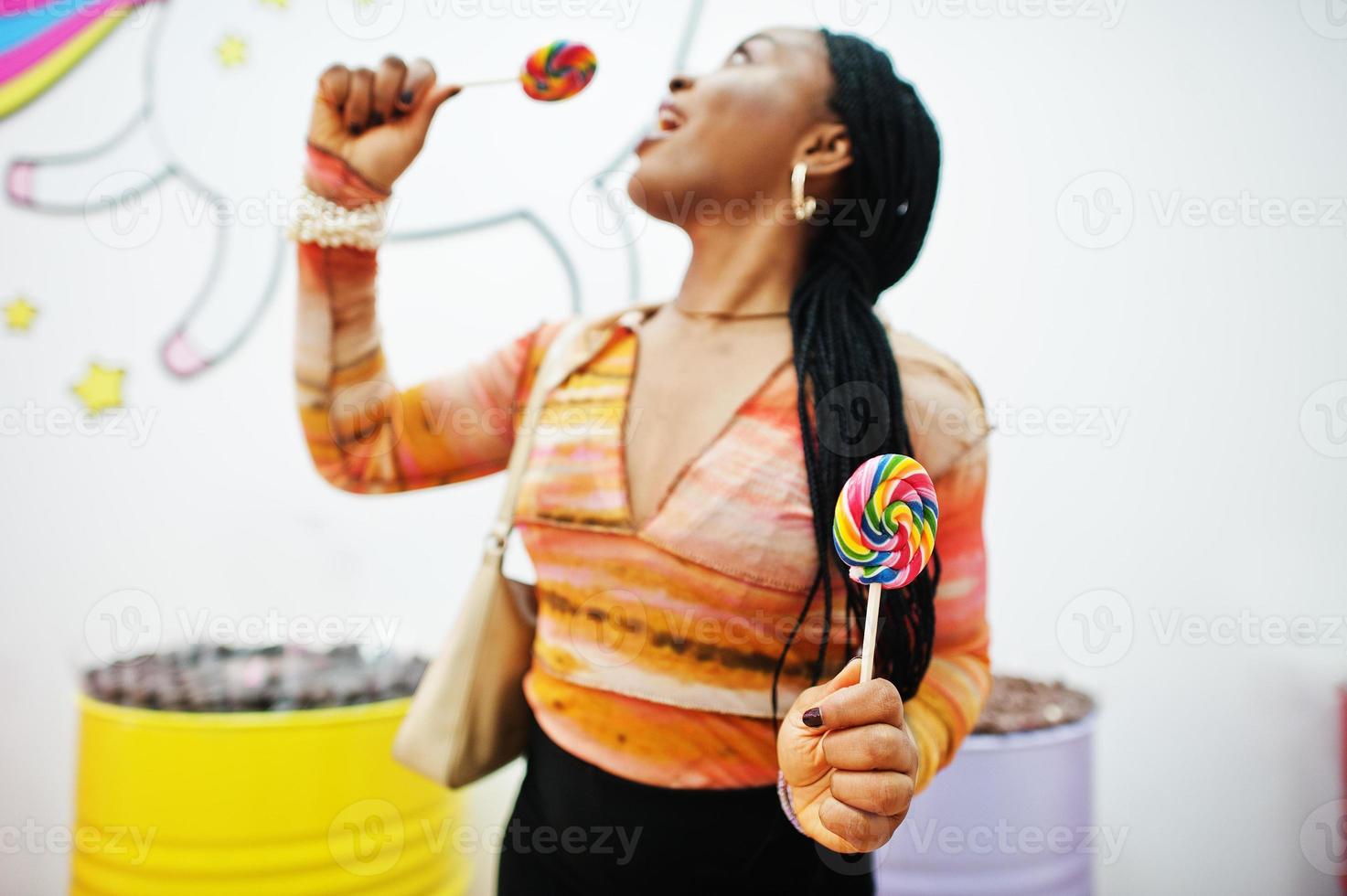 senhora milenar afro-americana na loja de doces com pirulitos. foto