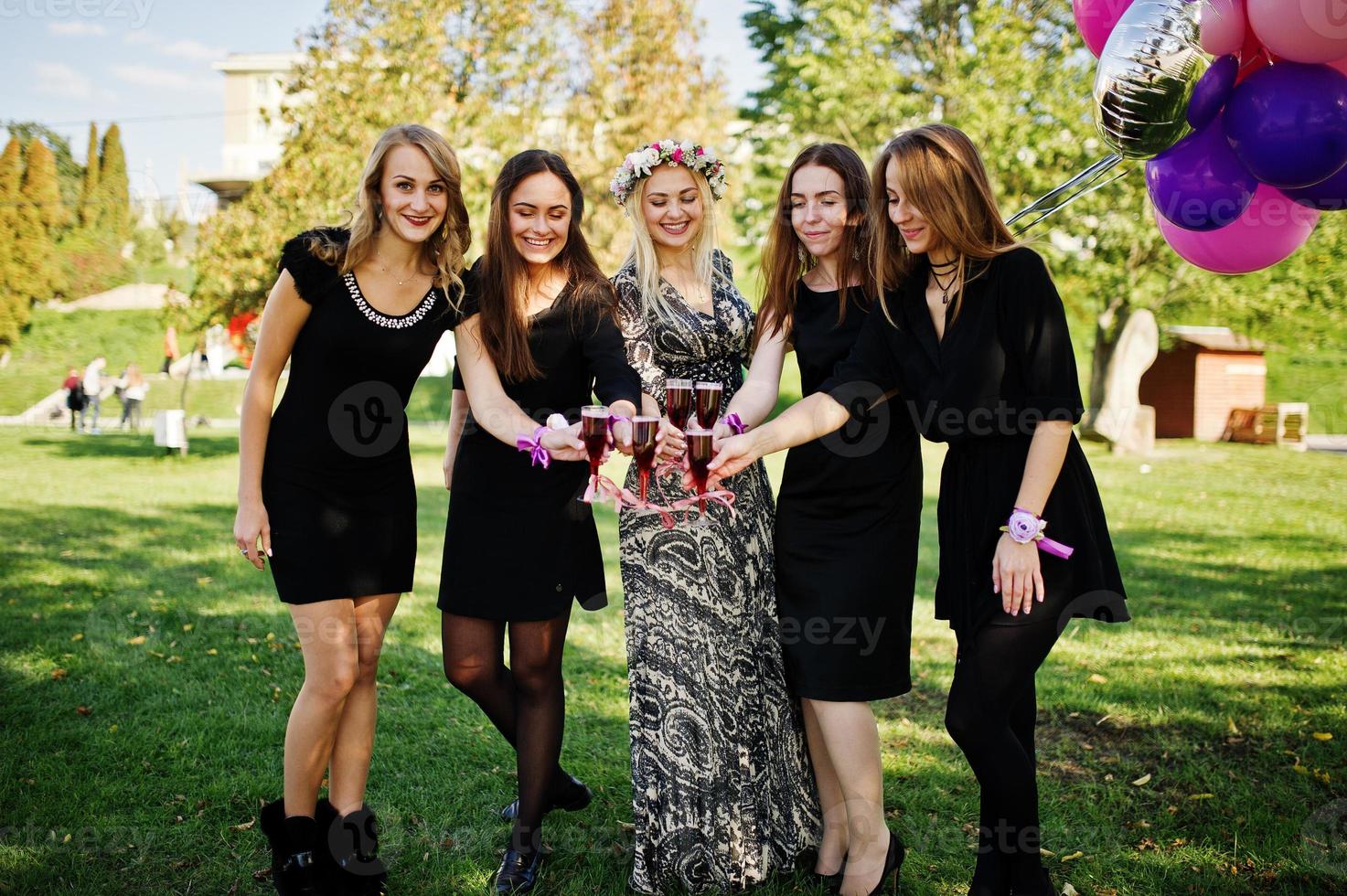 cinco garotas usam preto com balões bebendo champanhe vermelho na festa de despedida. foto