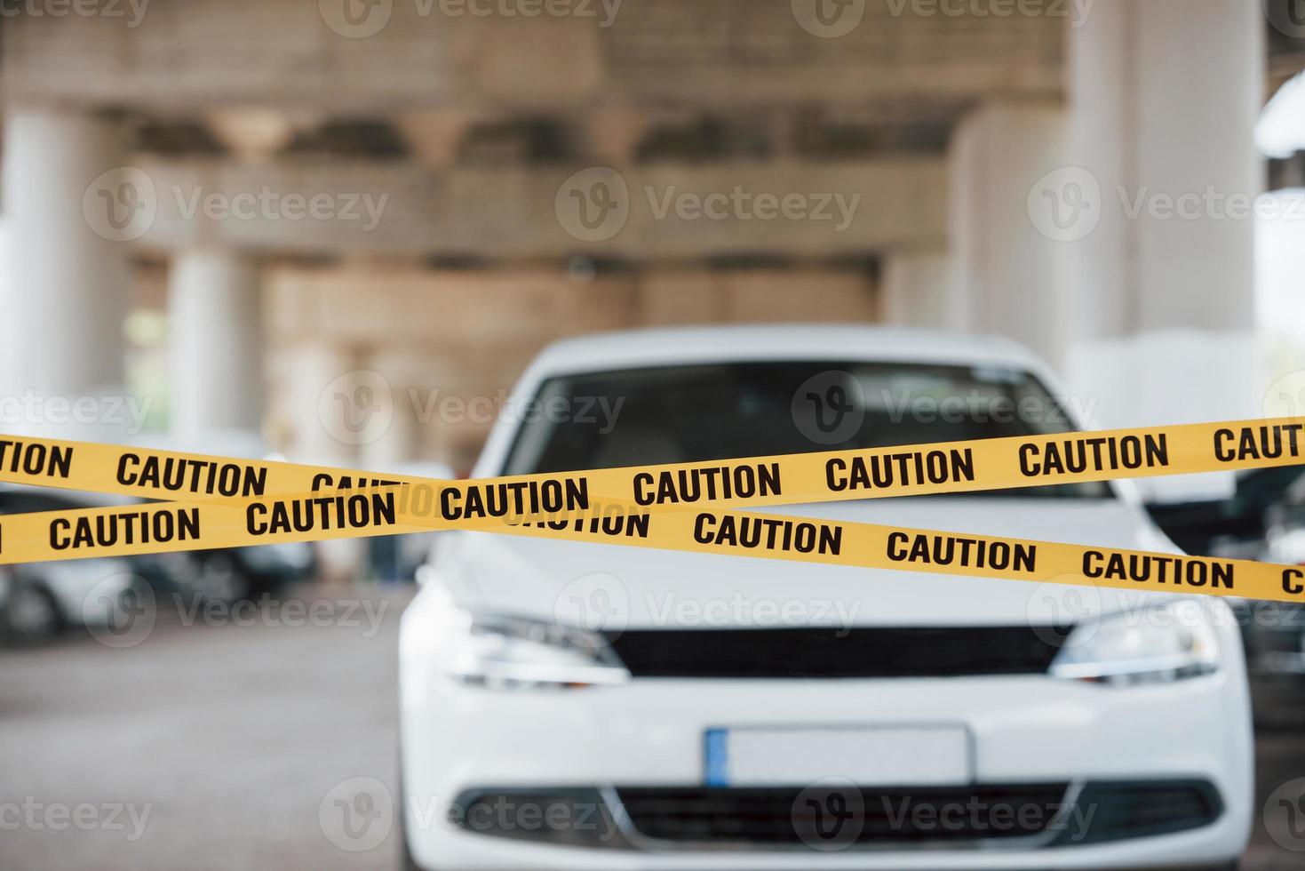 automóvel de cor branca. fita de advertência amarela perto do estacionamento durante o dia. cena do crime foto