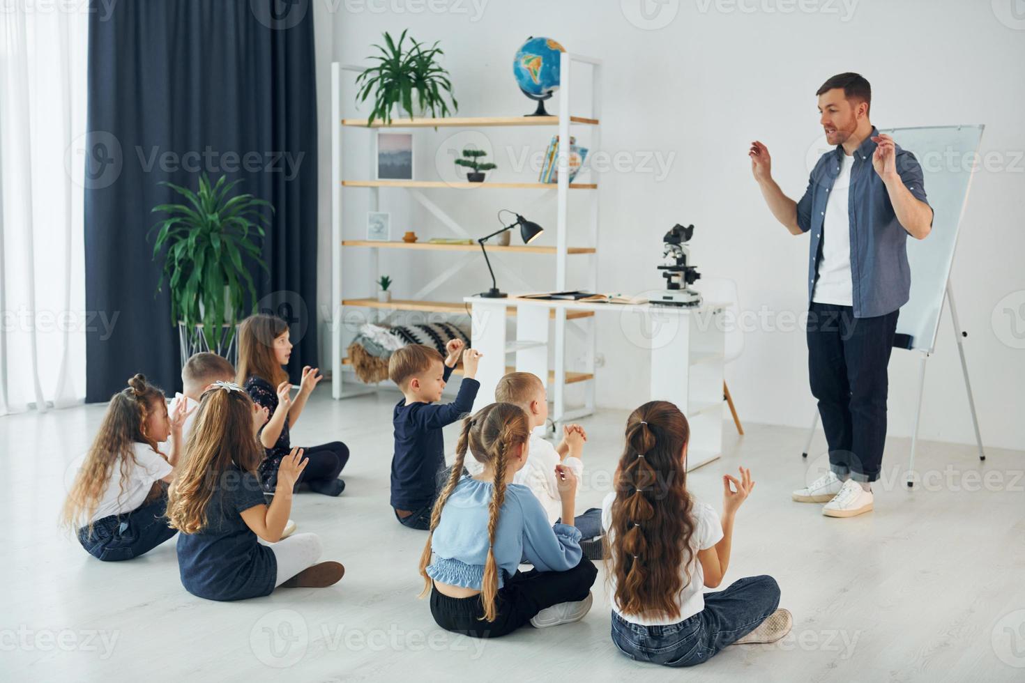 aprendendo a linguagem gestual. grupo de alunos de crianças em sala de aula na escola com professor foto