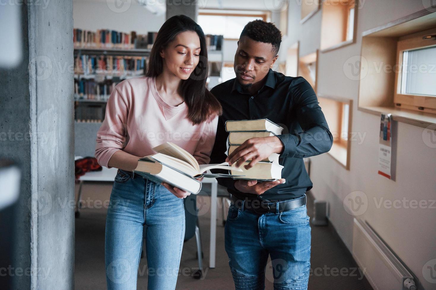 lindos jovens. estudantes multirraciais na biblioteca procurando as informações juntos foto