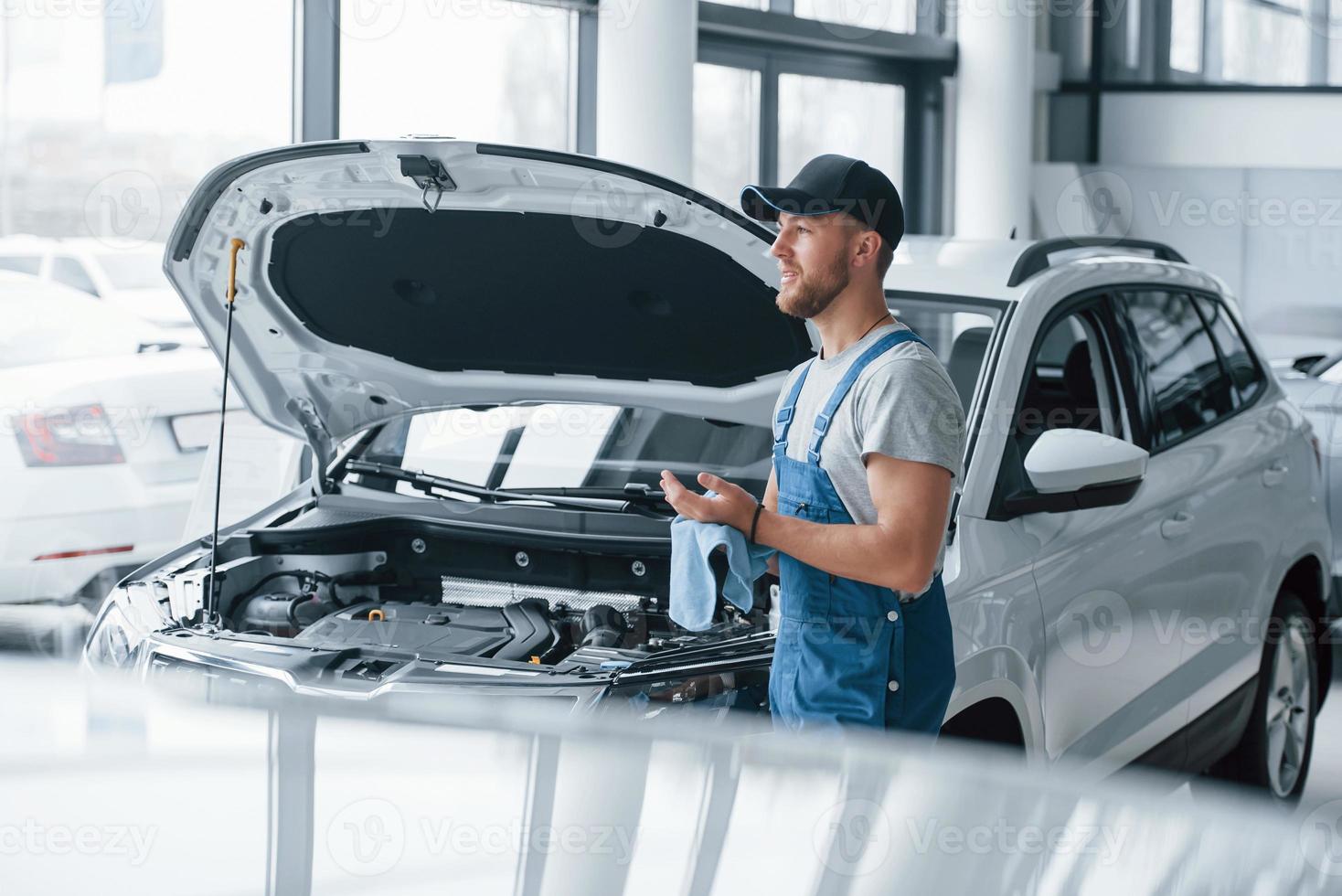 esperando o cliente. funcionário de uniforme de cor azul fica no salão de automóveis foto