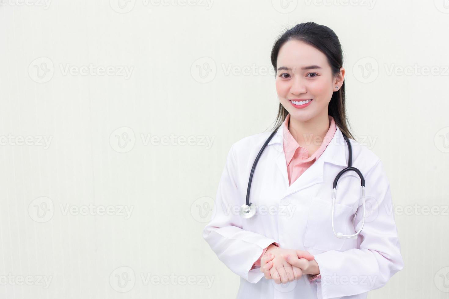 uma jovem e bela médica asiática de uniforme médico está de pé sorrindo de mãos dadas com fundo branco. novo conceito normal e de saúde foto