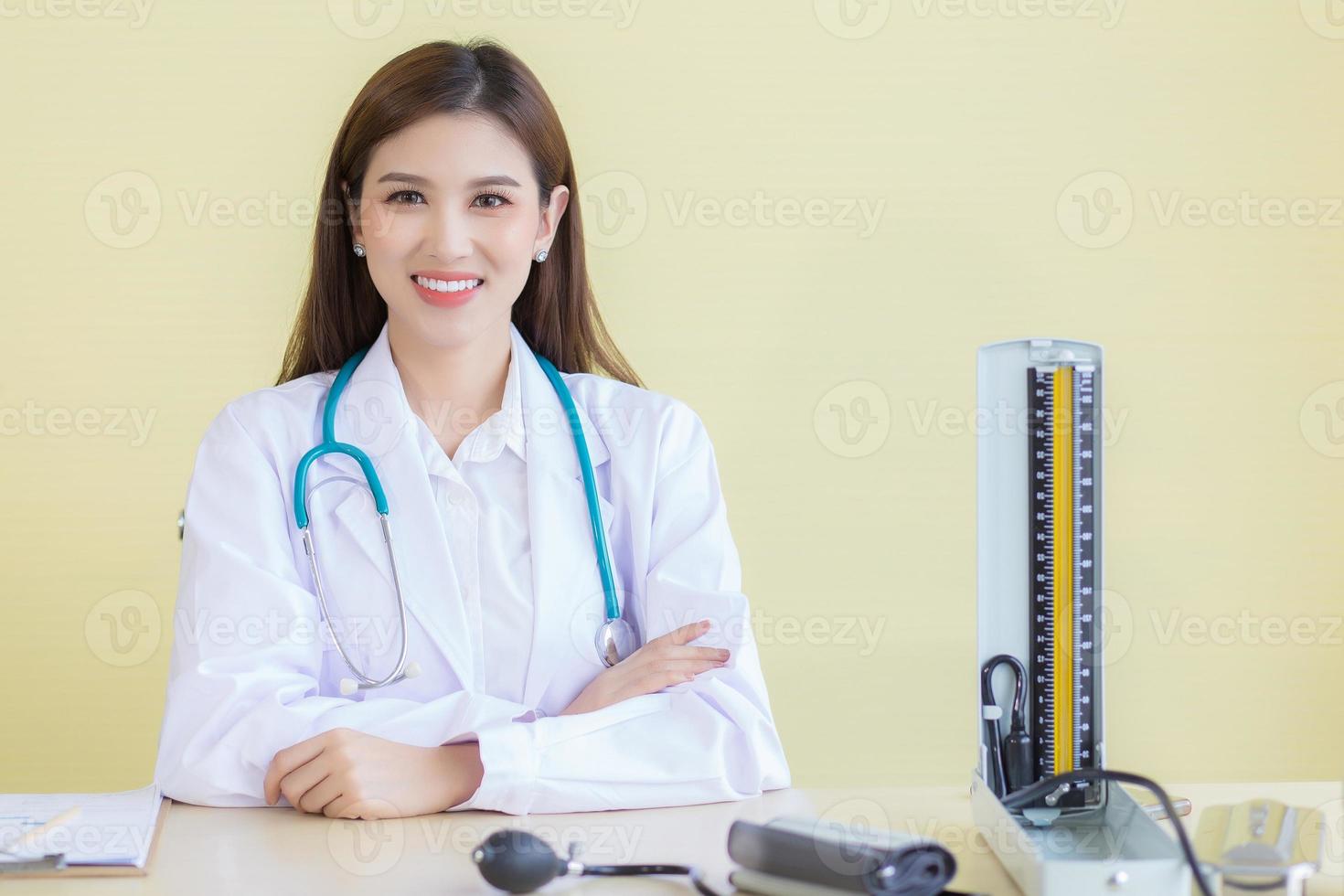 médico de mulher asiática com rosto sorridente, sente-se no escritório no hospital foto