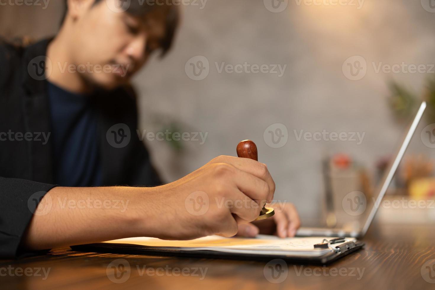 close-up da mão de uma pessoa carimbando com carimbo aprovado em documento de certificado em papel público na mesa, notário ou empresários trabalham em casa, isolados para proteção de coronavírus covid-19 foto